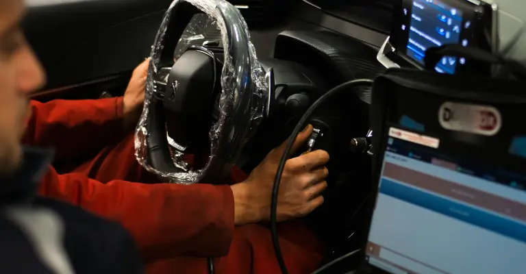 a photo of two mechanics doing a diag inside a car